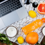 top view of citrus fruits as grapefruit coconut lemon with juice glasses and notebook on cloth and wooden background decorated with leaves